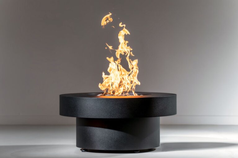 large, black, round, steel gas fire pit known as the Badlands with tall flames in white studio